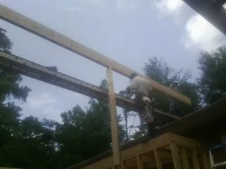 Carpenter setting a ridge beam over a new addition frame — Ice Dam Removal by Roofing Brothers in Cuddy
