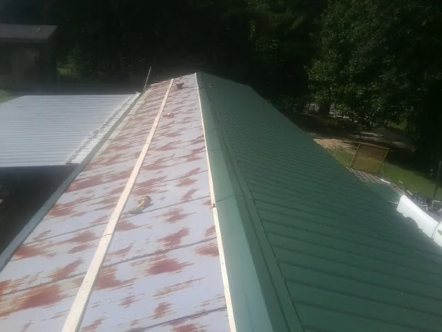 Old rusted panels beside newly installed green metal roofing — Wind Damage Roof Repair by Roofing Brothers in Cuddy