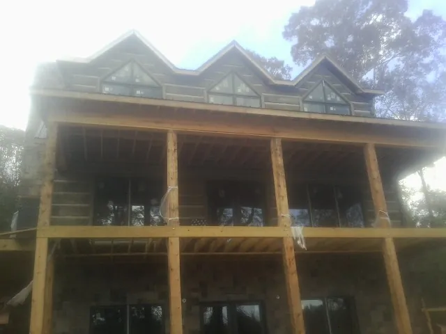 Dormers and porch framing on a large log home under construction — Roof Coating work by our crew in Cuddy