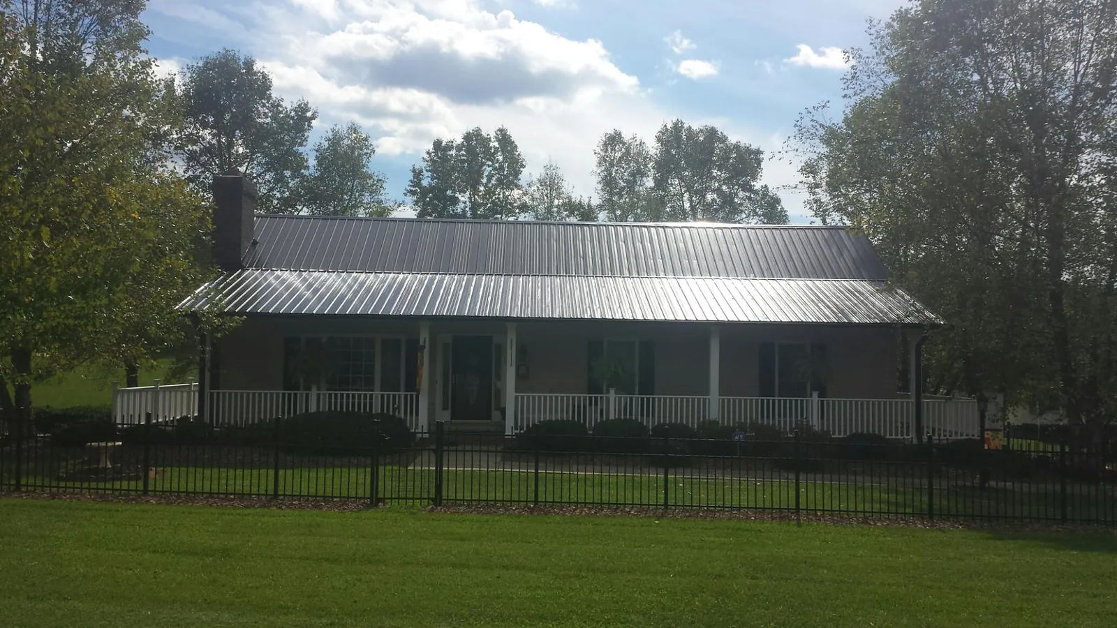 Gray metal roof on a brick ranch with a full width front porch — Gutter Guard Installation work by our crew in Cuddy