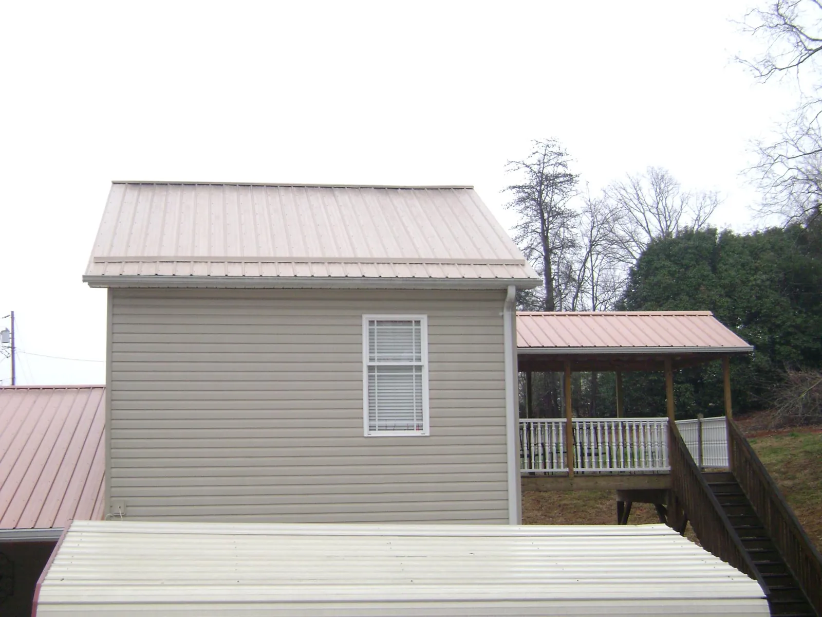 Tan metal roofs on a two story addition and attached porch, from a Roof Replacement job in Cuddy