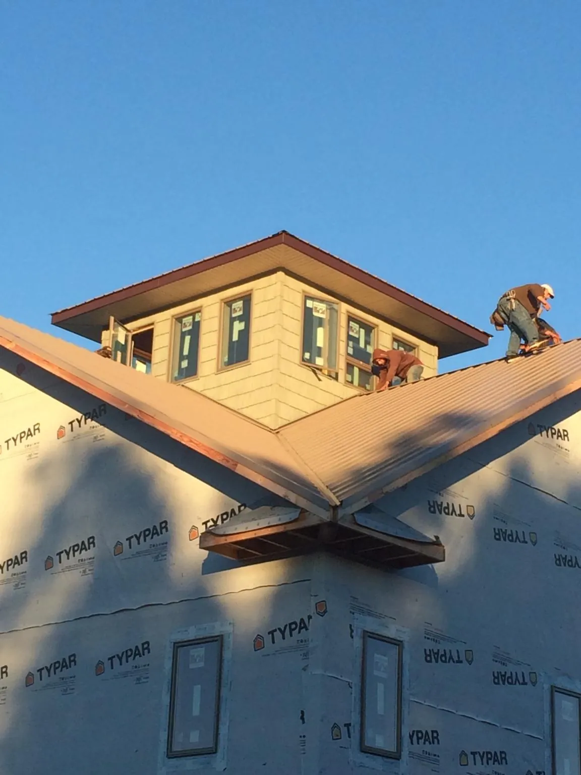 Roofers working around a rooftop cupola on a new metal roof at sunset — Roof Waterproofing in Cuddy by Roofing Brothers